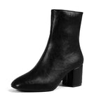 Side profile of black ankle boots on model, showing rear zip and chunky block heel