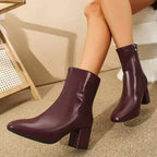 Angled front view of white ankle boot on white background showing patent finish and pointed toe