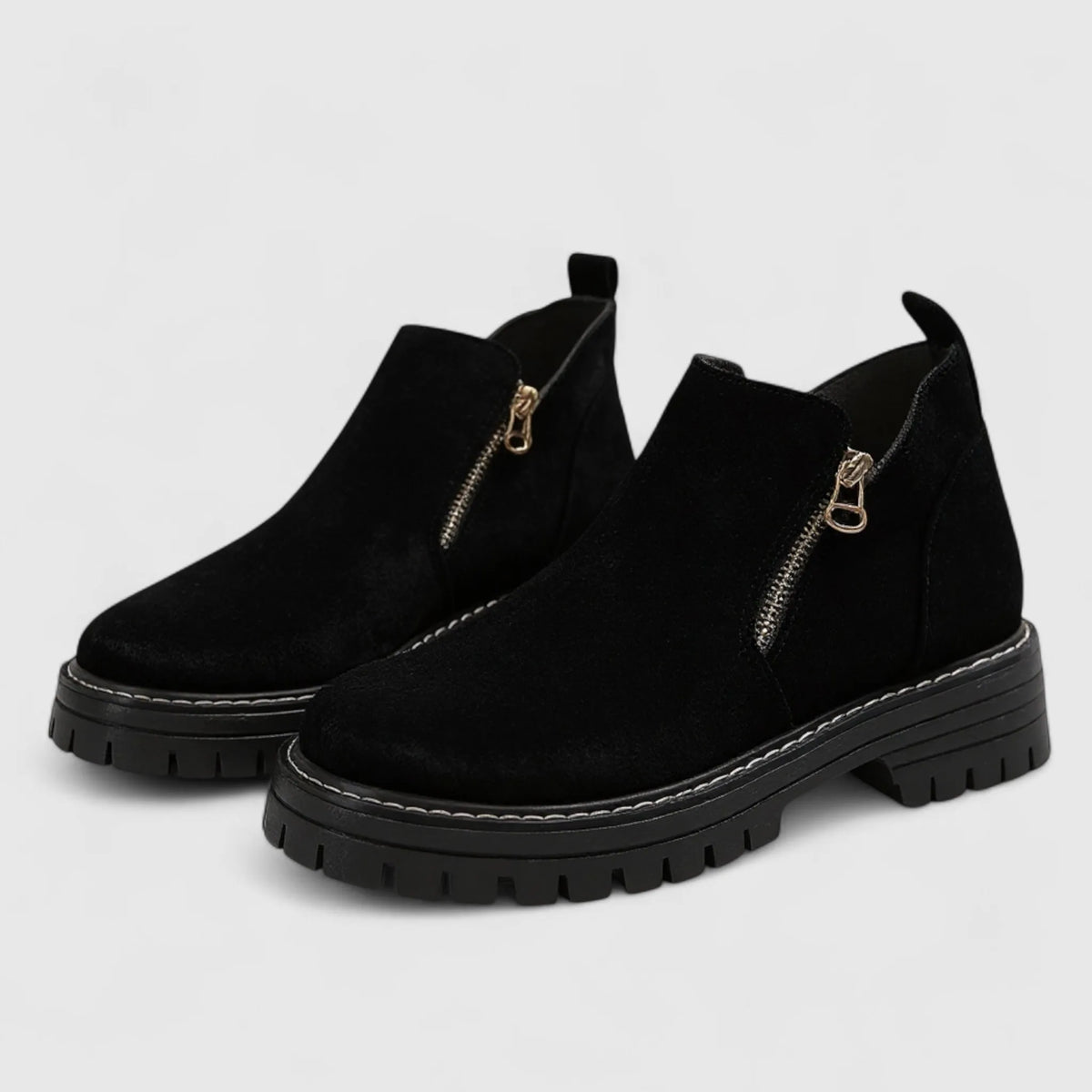 Black suede chunky ankle boots with gold side zip and lugged platform sole, angled view of both boots