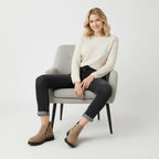 Model sitting on a chair wearing taupe suede ankle boots with black cropped jeans