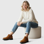 Close-up side view of taupe suede ankle boot showing gold zipper and lugged sole tread