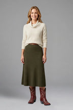 Woman wearing an ivory cowl-neck jumper, olive midi skirt and red embroidered ankle boots