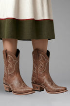 Brown leather ankle boots with cream embroidered stitching worn beneath a green and cream skirt