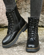 Side view of black lace-up ankle boots with side zip and chunky ridged sole, worn with grey skinny jeans