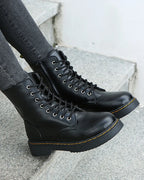 Front angle of black lace-up boots on stone steps, showing round toe and lug sole tread