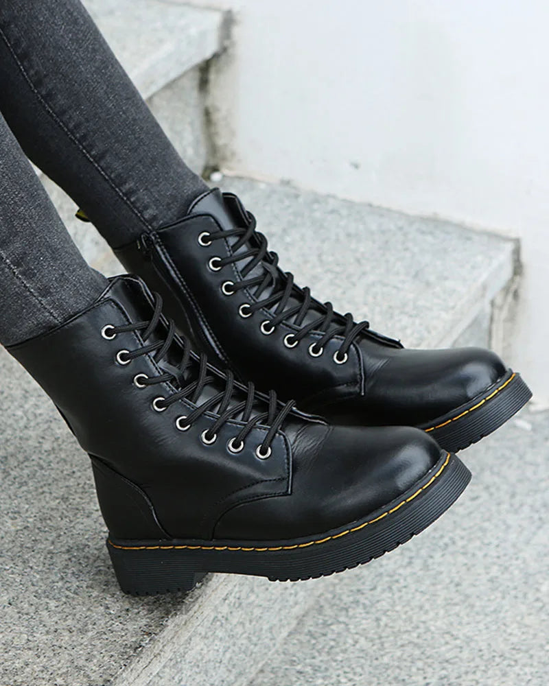 Front angle of black lace-up boots on stone steps, showing round toe and lug sole tread
