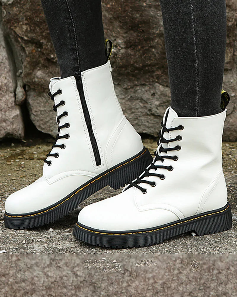 Close-up side profile of white boots highlighting the zip, eyelets and black chunky sole with yellow stitch