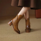 Close-up rear and side view of brown leather ankle boots with tassel zip pull, worn beneath a flared skirt