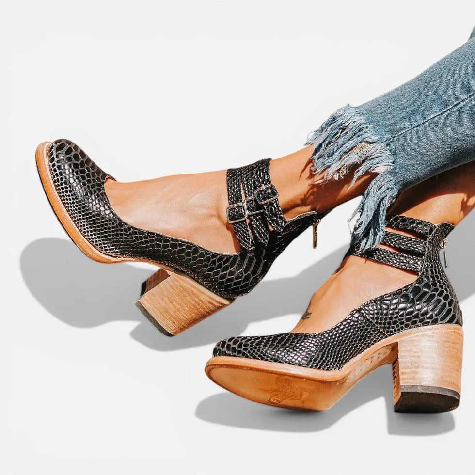 Black snake-embossed leather platform heels with cutout ankle straps, styled with frayed denim jeans