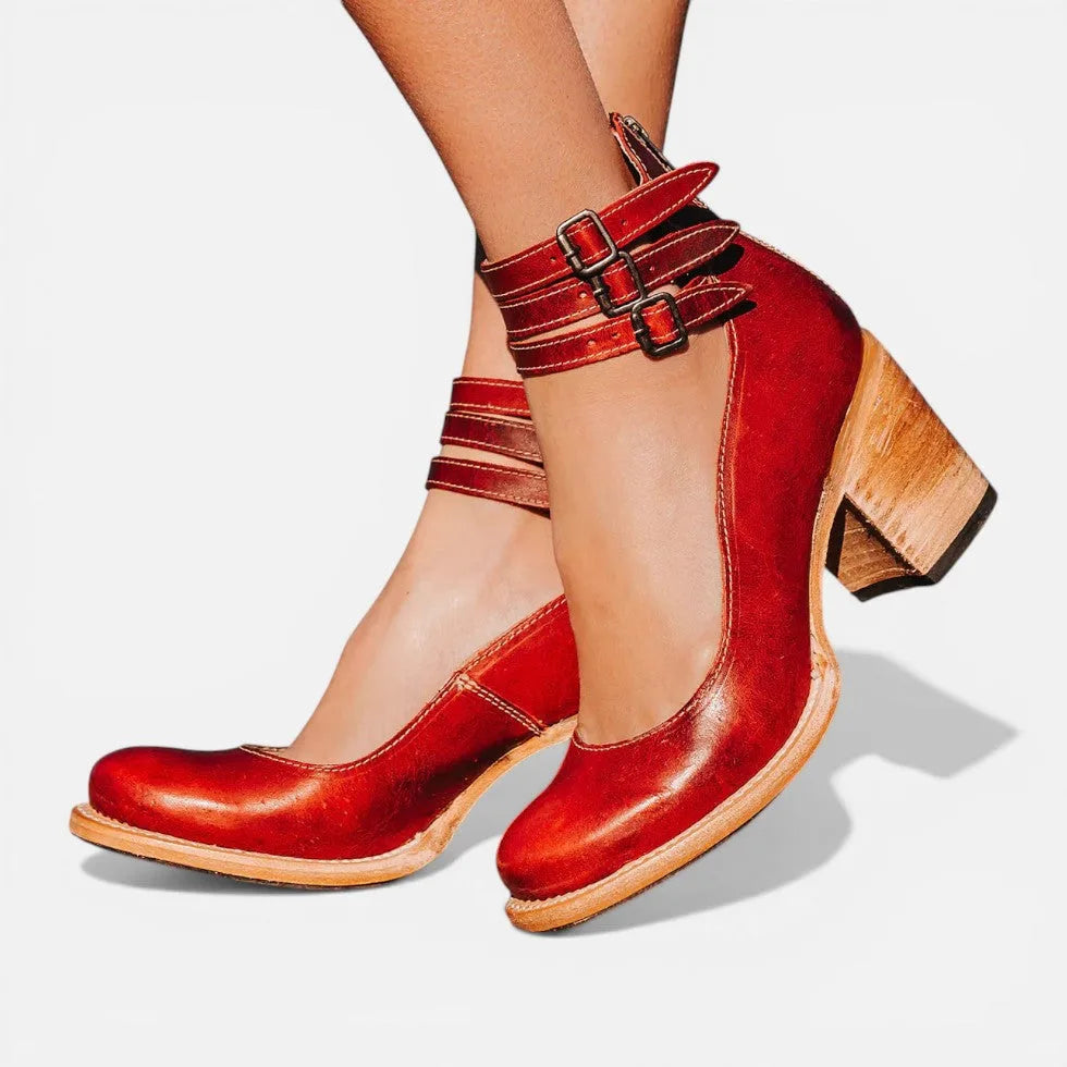 Red leather ankle boots with triple buckle ankle straps, rounded toe and block heel, worn with bare legs
