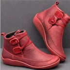 Side and front view of red leather ankle boots with stitched panels and a low wedge sole