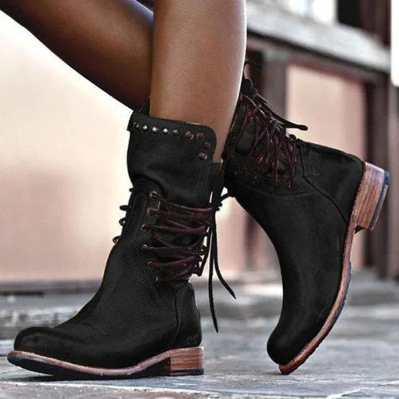 Black leather lace-up boots shown from behind with dark laces criss-crossing up to the studded ankle cuff