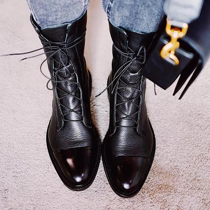 Pair of black lace-up ankle boots worn with cropped denim jeans, laces untied at the top