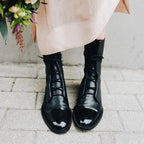 Black leather ankle boots paired with jeans and a black handbag with gold hardware in the background