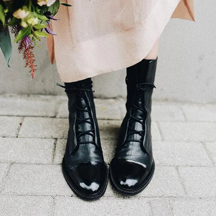 Black leather ankle boots paired with jeans and a black handbag with gold hardware in the background