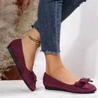Side profile of bordeaux suede-effect ballet flats with bow trim worn with light denim jeans