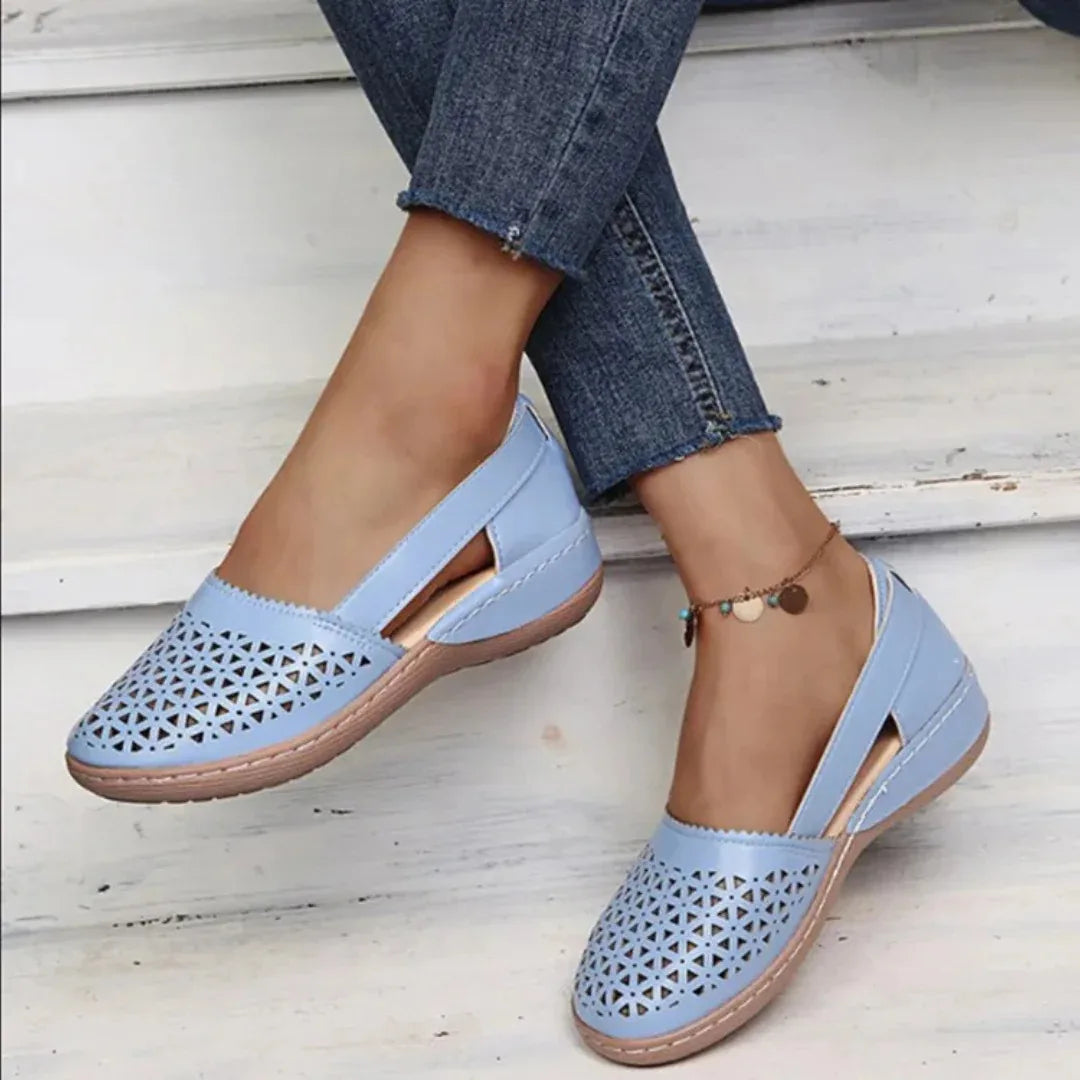 Blue perforated leather flat showing the cushioned wedge sole and scalloped edge detail