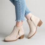 Bone faux-suede ankle boot with gold-tone zip detail, paired with light denim, showing rounded toe and block heel