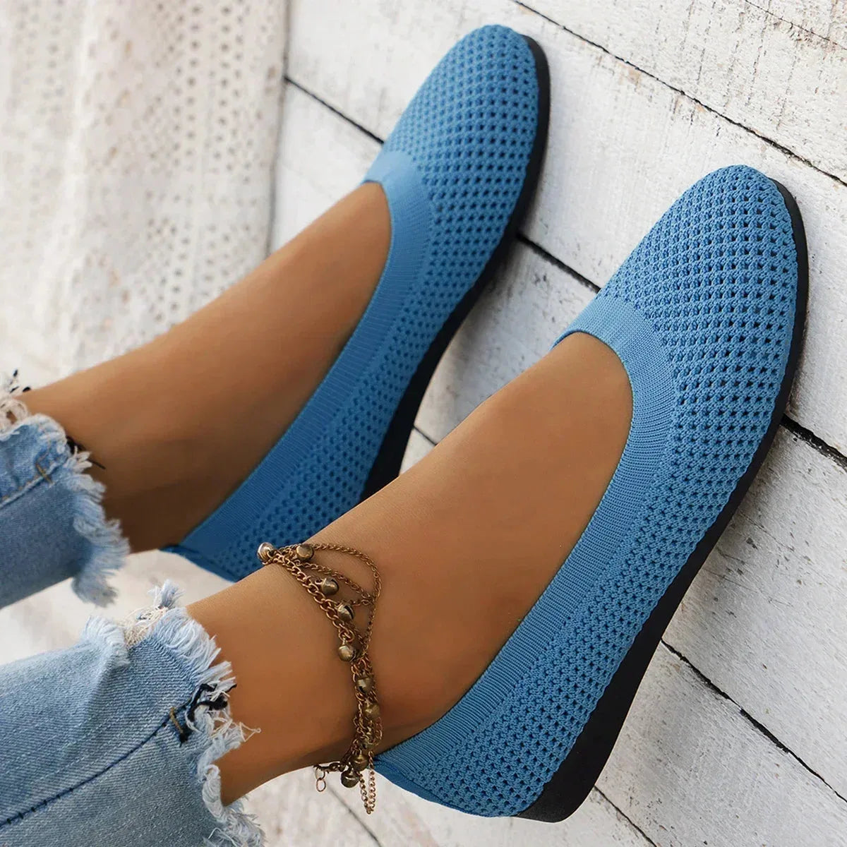 Sky blue ballet flat paired with distressed denim, showing the slip-on fit around the ankle