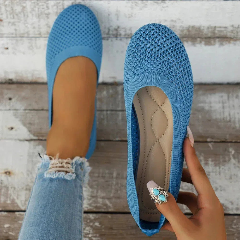 Sky blue knit ballet flats, one worn on foot and one held by hand showing tan insole