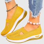 Pair of black knitted slip-on trainers on plain background showing rounded toe shape