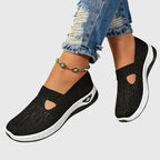 Black knitted slip-on trainer shown from front with side cut-out and gemstone anklet