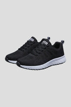 Angled view of black knit mesh trainers with white cushioned sole and lace-up closure