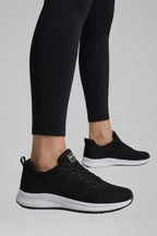 Side profile of black knit trainer on foot, highlighting mesh texture and white midsole