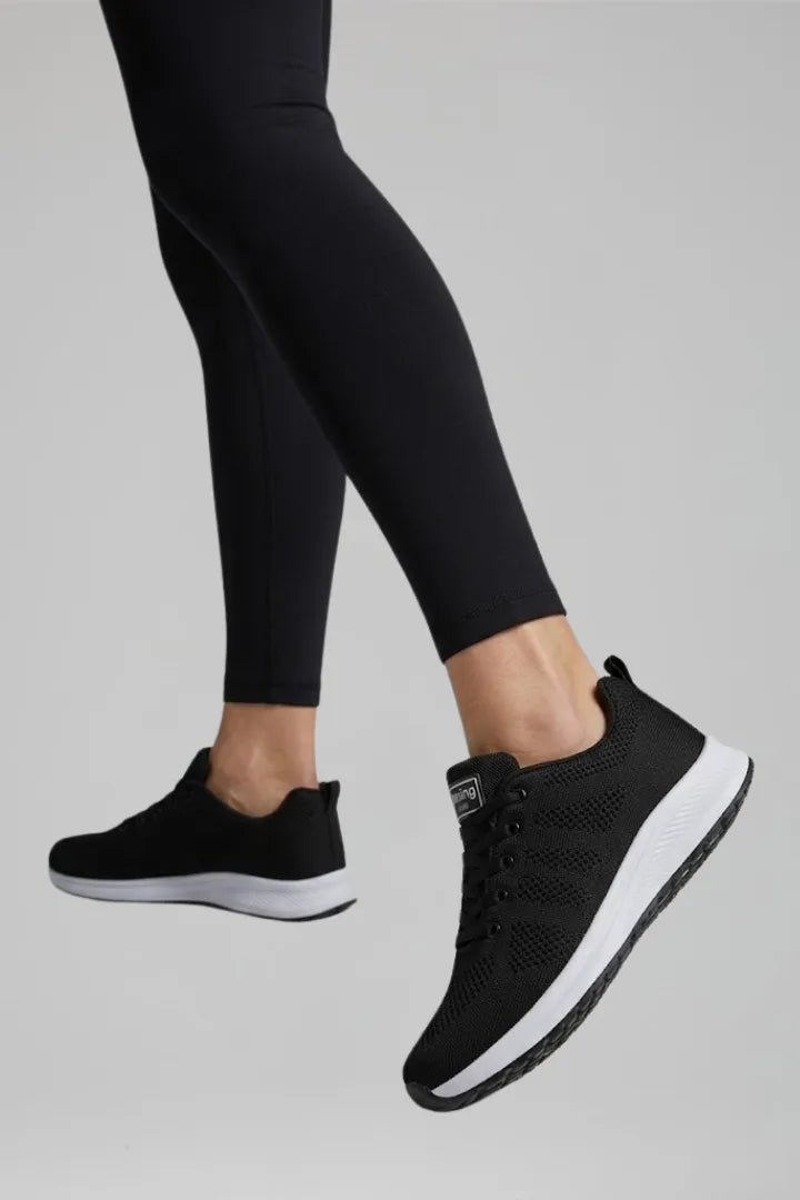 Close-up side view of black trainer mid-step, showing thick white cushioned sole