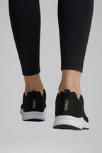 Back view of black trainers on feet, showing heel pull tab with text branding and white sole