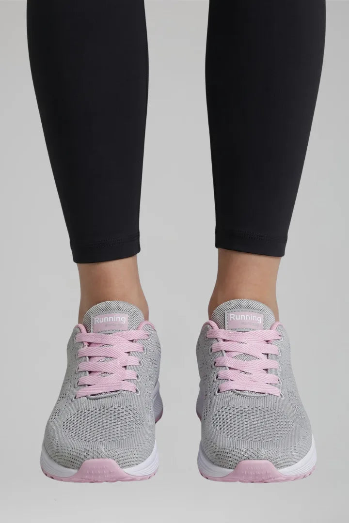 Front view of grey and pink knit trainers with pink laces worn with black leggings