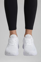 Front view of white knit mesh trainers with white laces and white sole worn with black leggings