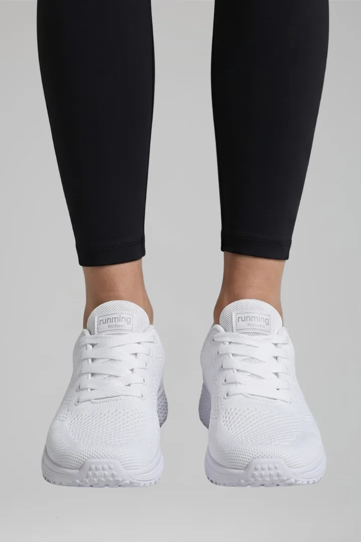 Front view of white knit mesh trainers with white laces and white sole worn with black leggings