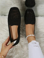 Black glitter-knit slip-on flats with mesh toe detail and tan insole, held by hand