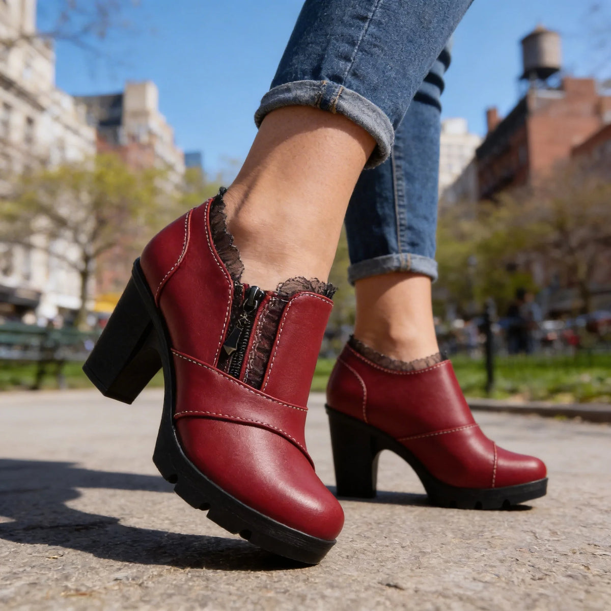 Side view of burgundy leather ankle boot with lace-trimmed collar, zip fastening and block heel on model