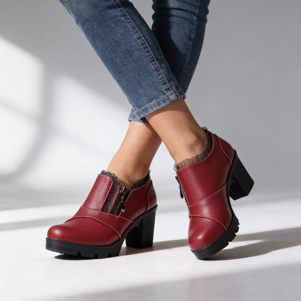 Pair of white ankle boots on model showing block heel, platform sole and ruffled lace collar