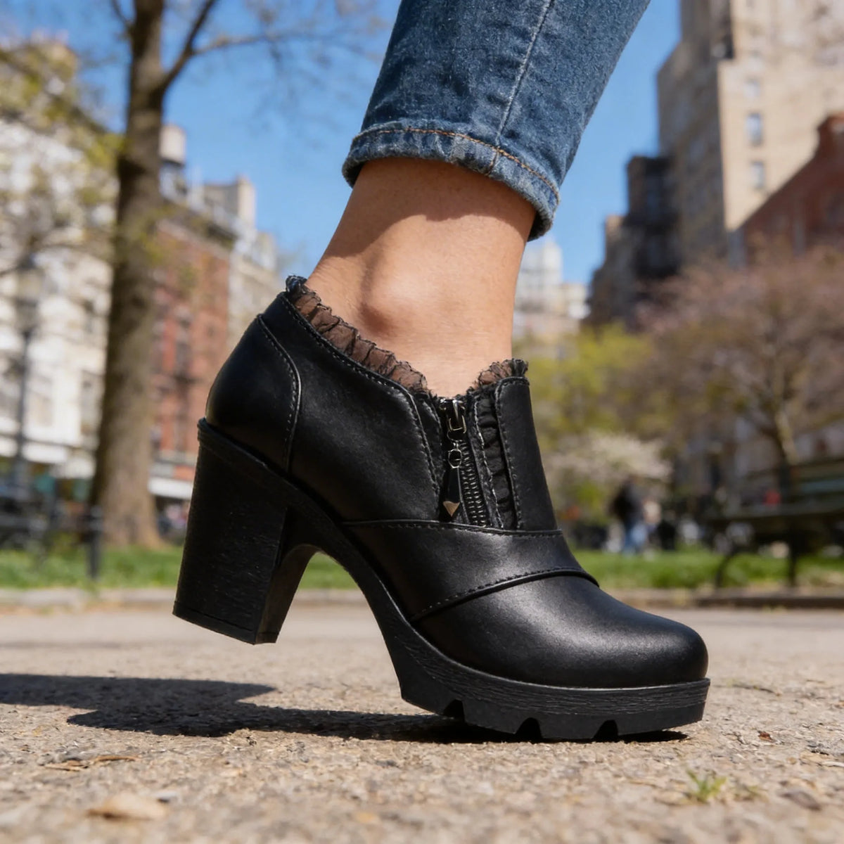White ankle boots on crossed legs in outdoor setting showing block heel and lace collar detail