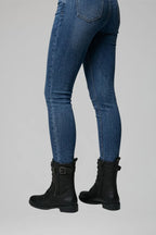 Back view of black combat boots showing pull tab and buckle strap at the shaft, worn with jeans
