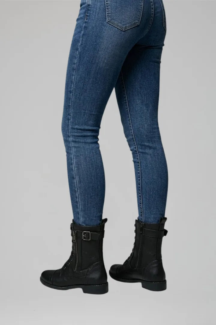 Back view of black combat boots showing pull tab and buckle strap at the shaft, worn with jeans