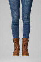 Front view of brown lace-up combat boots with side zip and tan sole, worn with blue skinny jeans