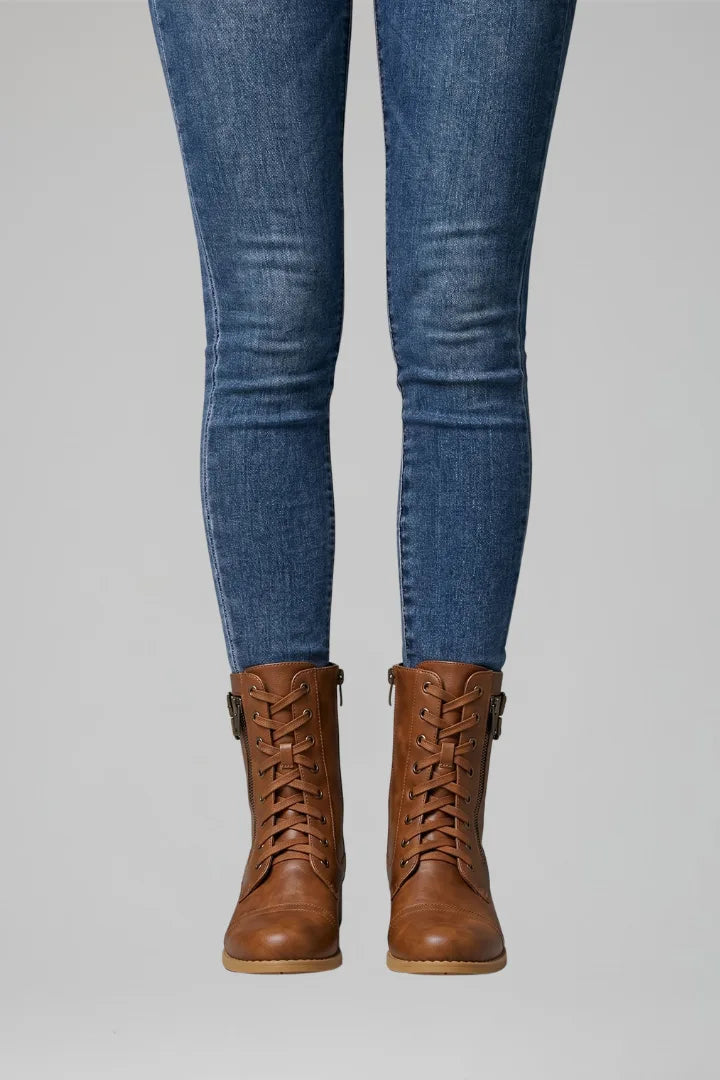 Front view of brown lace-up combat boots with side zip and tan sole, worn with blue skinny jeans