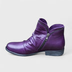 Side view of a purple leather ankle boot with slouched shaft, side zip and stacked block heel