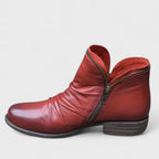 Deep red leather ankle boot in profile showing ruched leather, contrast zip and burnished finish