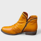 Mustard yellow leather ankle boot with slouch detailing, exposed zip pull and low stacked heel