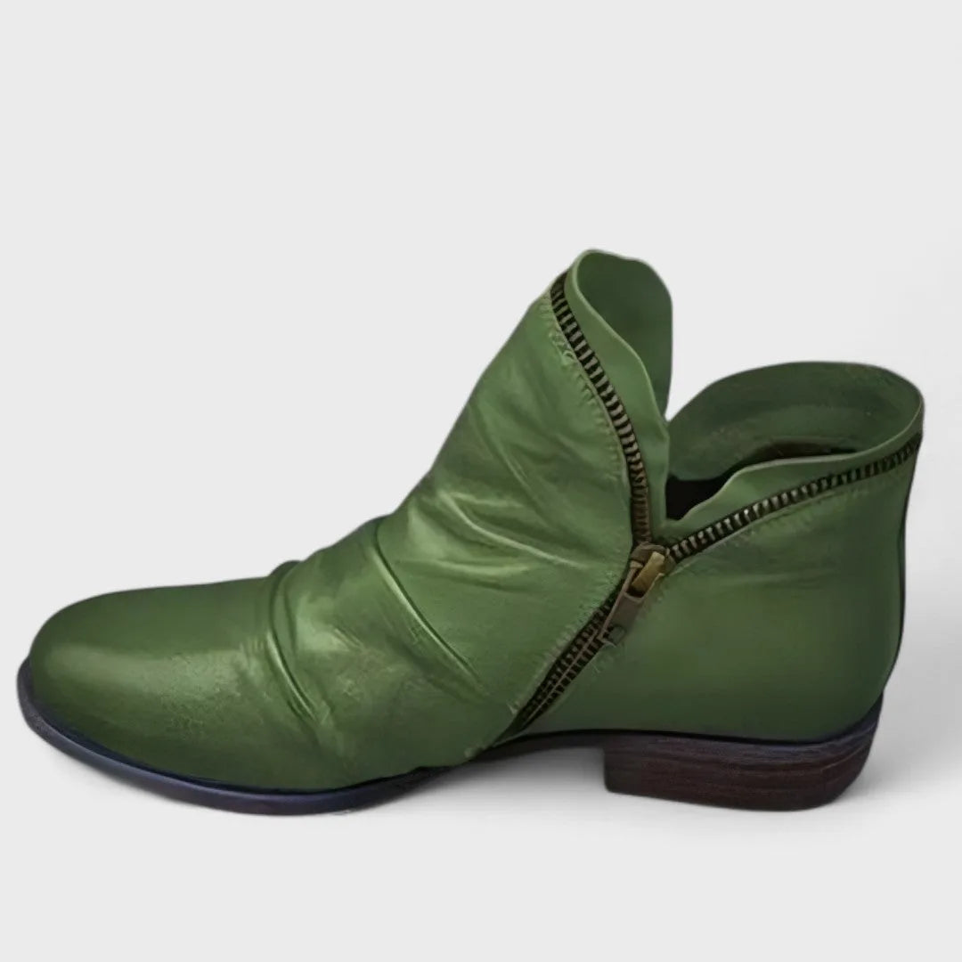Olive green leather ankle boot photographed side-on with wrinkled shaft and asymmetric zip trim