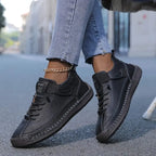 Black leather lace-up trainer with hand-stitched sole detail, shown on foot with cropped jeans