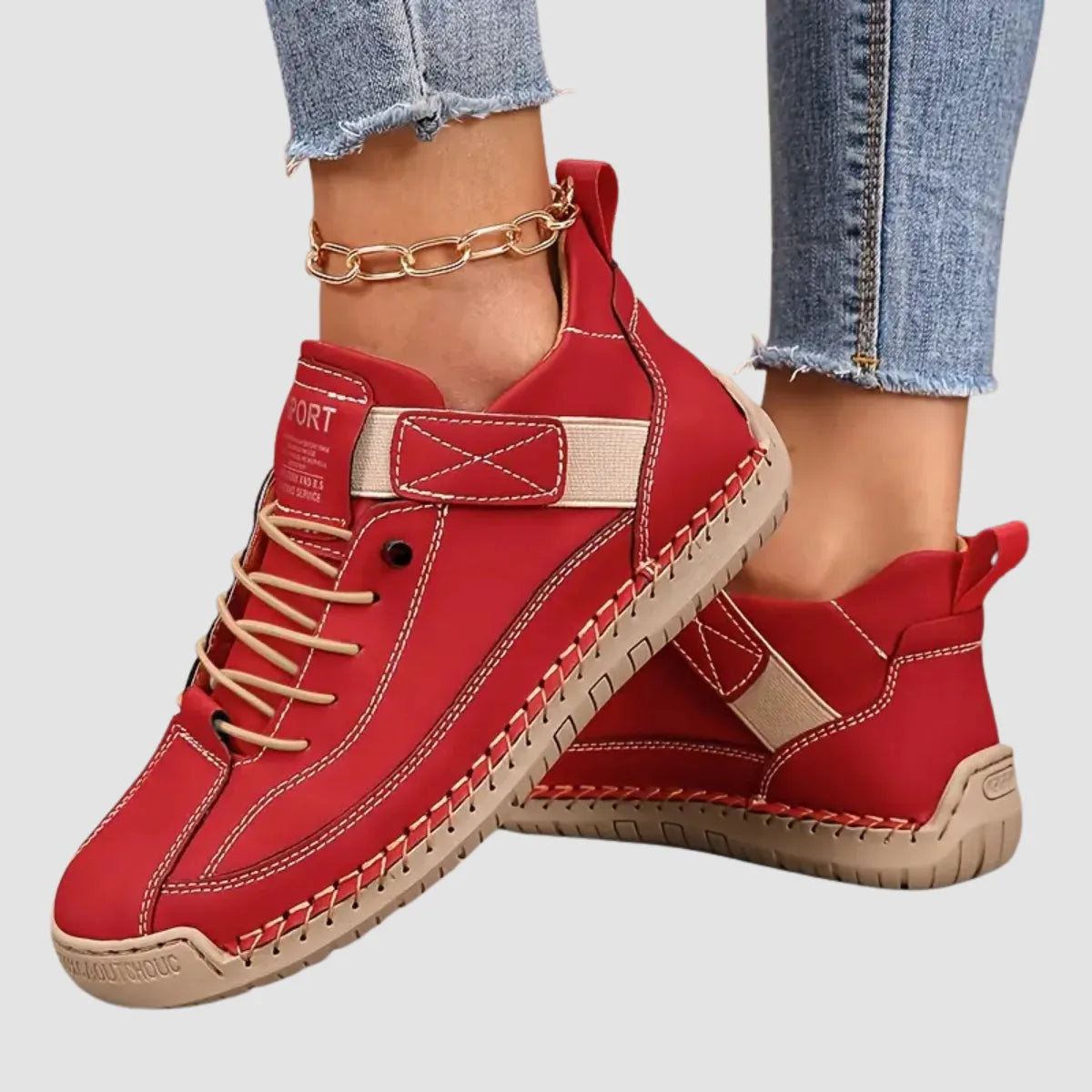 Red leather trainer with contrasting tan laces and strap, close-up side view