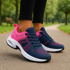Side view of pink and navy mesh trainer with white air-cushion sole and lace-up front, worn on foot outdoors