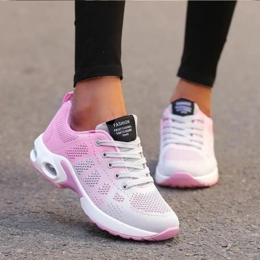 Side view of pink and grey ombre mesh trainer with white laces and pink outsole, worn while walking