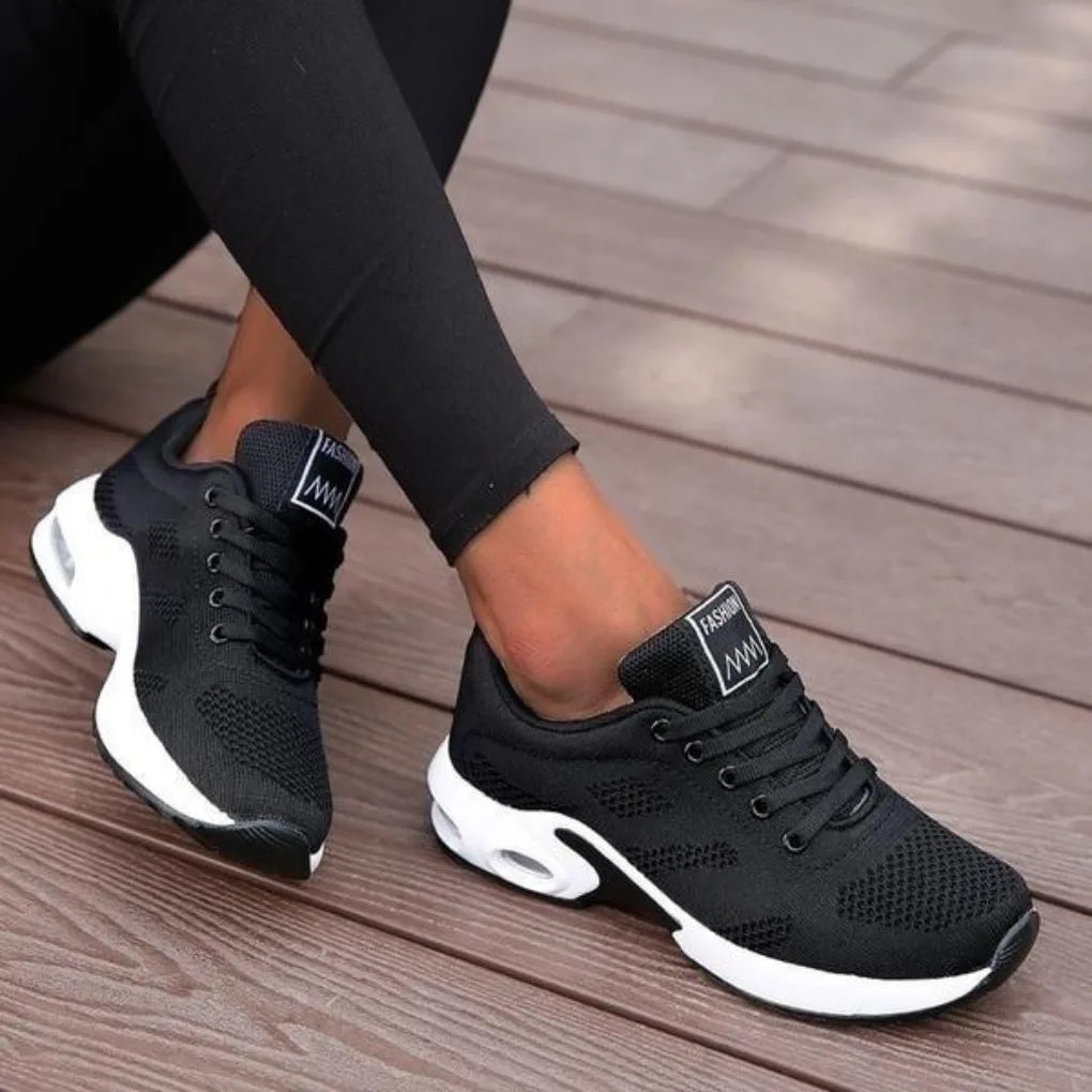 Angled view of black mesh trainers with white air-cushion sole and Fashion branded heel tab